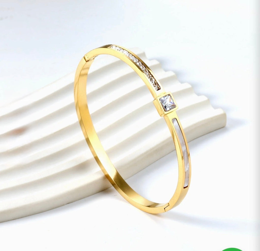 Aurelia Mother-of-Pearl Bangle – gold version styled on white ridged surface